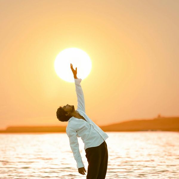 Silhouette of a man in a meditative pose at sunset.
